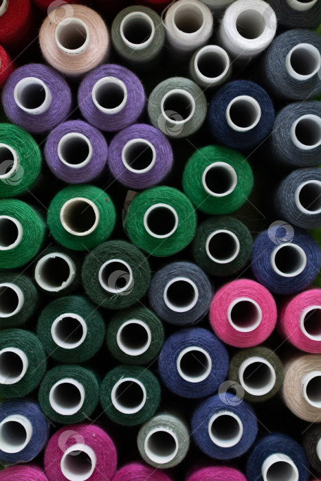 Скачать Большая группа разноцветных катушек с нитками для шитья на рабочем месте в небольшом ателье. вид сверху фотосток Ozero
