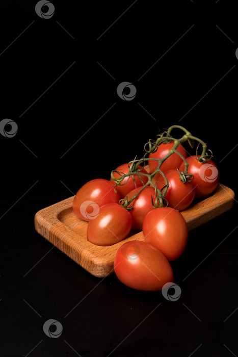 Скачать Свежие красные помидоры черри на деревянной тарелке на черном фоне фотосток Ozero