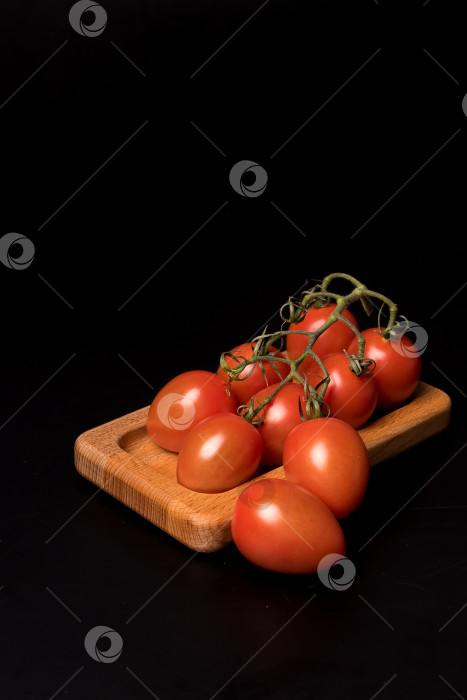Скачать Свежие красные помидоры черри на деревянной тарелке на черном фоне фотосток Ozero