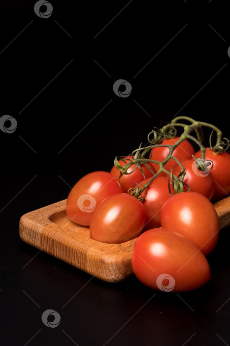 Скачать Свежие красные помидоры черри на деревянной тарелке на черном фоне фотосток Ozero