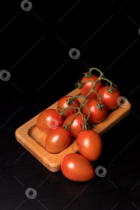 Скачать Свежие красные помидоры черри на деревянной тарелке на черном фоне фотосток Ozero