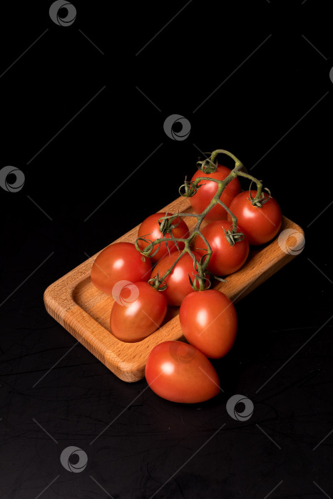 Скачать Свежие красные помидоры черри на деревянной тарелке на черном фоне фотосток Ozero