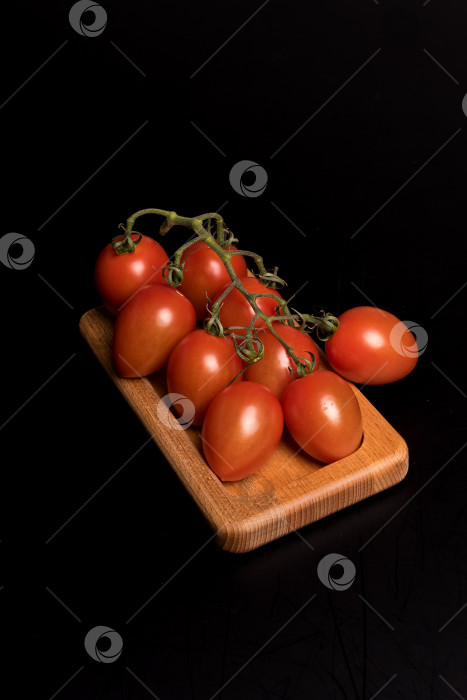 Скачать Свежие красные помидоры черри на деревянной тарелке на черном фоне фотосток Ozero