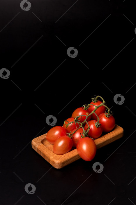 Скачать Свежие красные помидоры черри на деревянной тарелке на черном фоне фотосток Ozero
