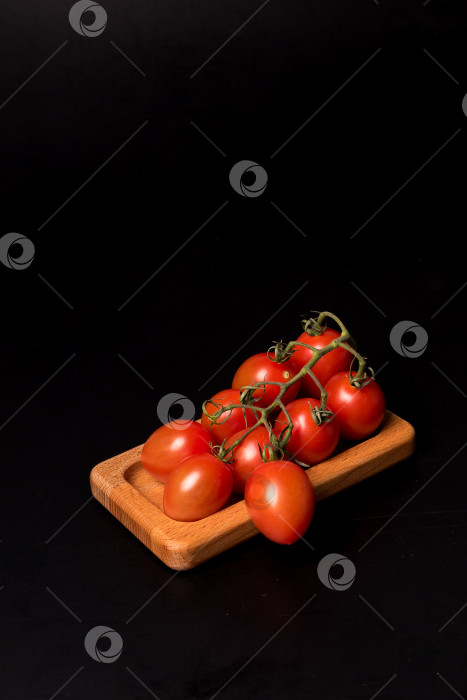 Скачать Свежие красные помидоры черри на деревянной тарелке на черном фоне фотосток Ozero