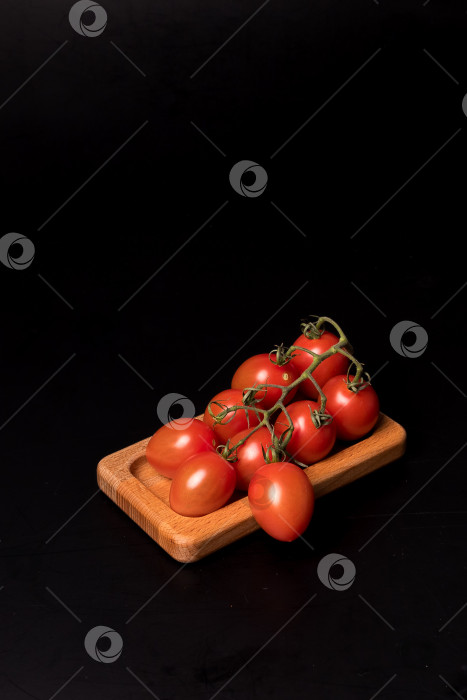 Скачать Свежие красные помидоры черри на деревянной тарелке на черном фоне фотосток Ozero
