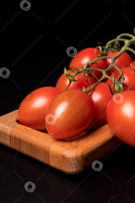 Скачать Свежие красные помидоры черри на деревянной тарелке на черном фоне фотосток Ozero
