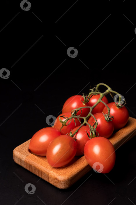 Скачать Свежие красные помидоры черри на деревянной тарелке на черном фоне фотосток Ozero