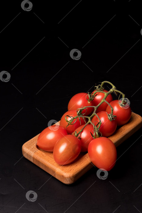 Скачать Свежие красные помидоры черри на деревянной тарелке на черном фоне фотосток Ozero