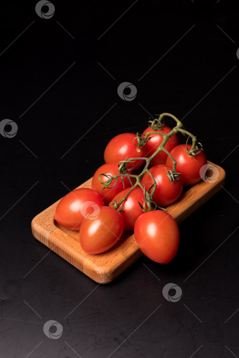 Скачать Свежие красные помидоры черри на деревянной тарелке на черном фоне фотосток Ozero