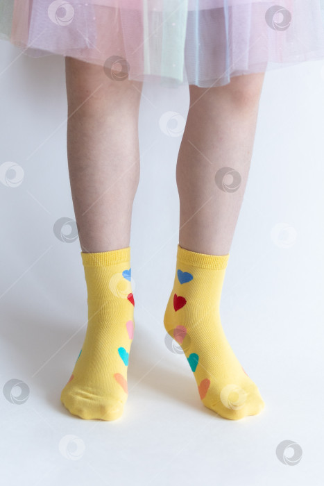 Скачать красивые ножки в теплых носочках с принтом в виде сердечек на белом фоне крупным планом. фотосток Ozero