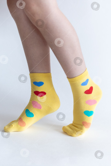 Скачать красивые ножки в теплых носочках с принтом в виде сердечек на белом фоне крупным планом. фотосток Ozero