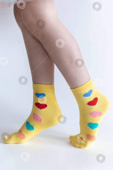 Скачать красивые ножки в теплых носочках с принтом в виде сердечек на белом фоне крупным планом. фотосток Ozero