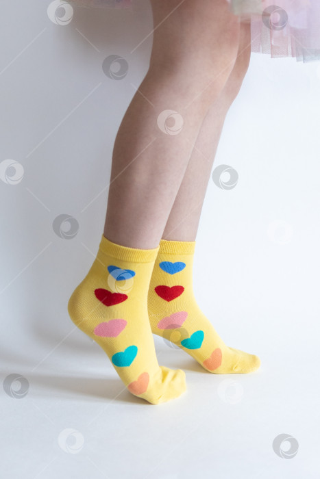 Скачать красивые ножки в теплых носочках с принтом в виде сердечек на белом фоне крупным планом. фотосток Ozero