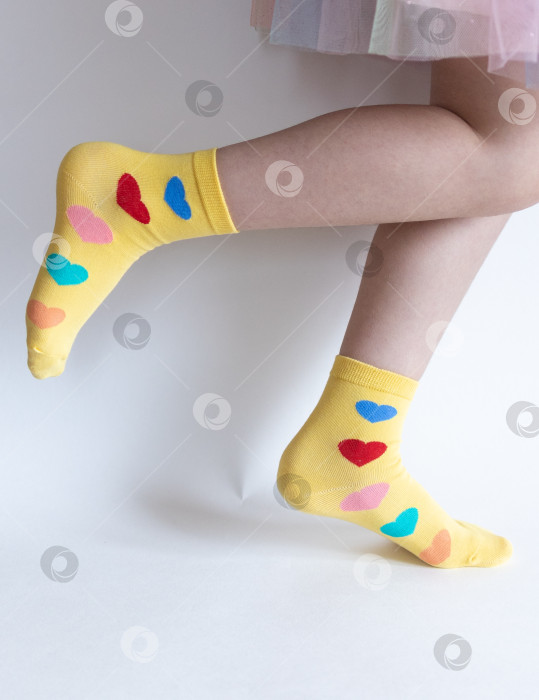 Скачать красивые ножки в теплых носочках с принтом в виде сердечек на белом фоне крупным планом. фотосток Ozero