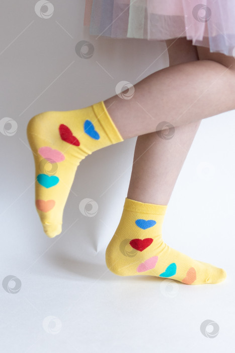 Скачать красивые ножки в теплых носочках с принтом в виде сердечек на белом фоне крупным планом. фотосток Ozero