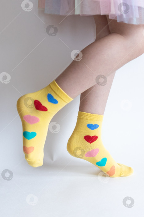 Скачать красивые ножки в теплых носочках с принтом в виде сердечек на белом фоне крупным планом. фотосток Ozero