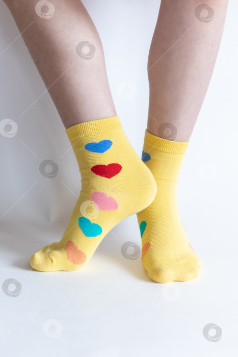 Скачать красивые ножки в теплых носочках с принтом в виде сердечек на белом фоне крупным планом. фотосток Ozero