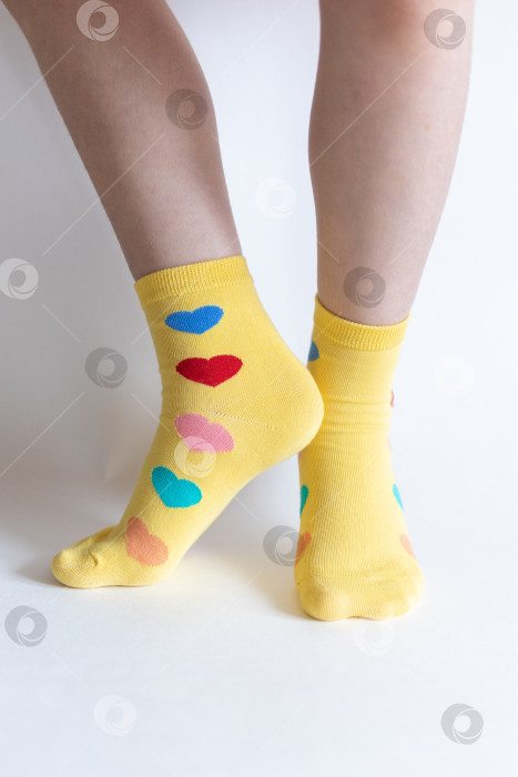 Скачать красивые ножки в теплых носочках с принтом в виде сердечек на белом фоне крупным планом. фотосток Ozero