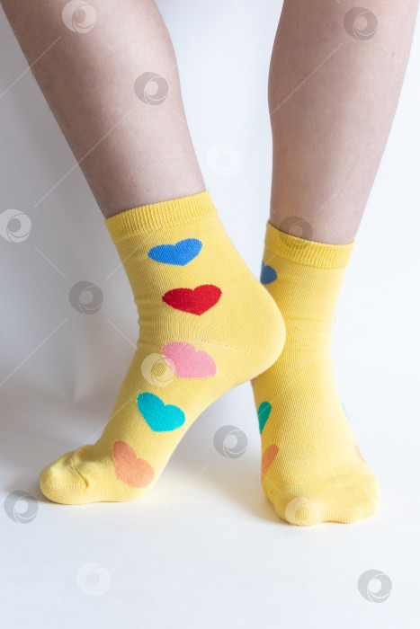 Скачать красивые ножки в теплых носочках с принтом в виде сердечек на белом фоне крупным планом. фотосток Ozero