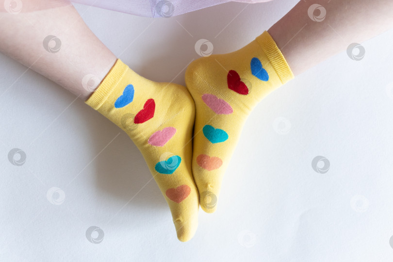 Скачать красивые ножки в теплых носочках с принтом в виде сердечек на белом фоне крупным планом. фотосток Ozero