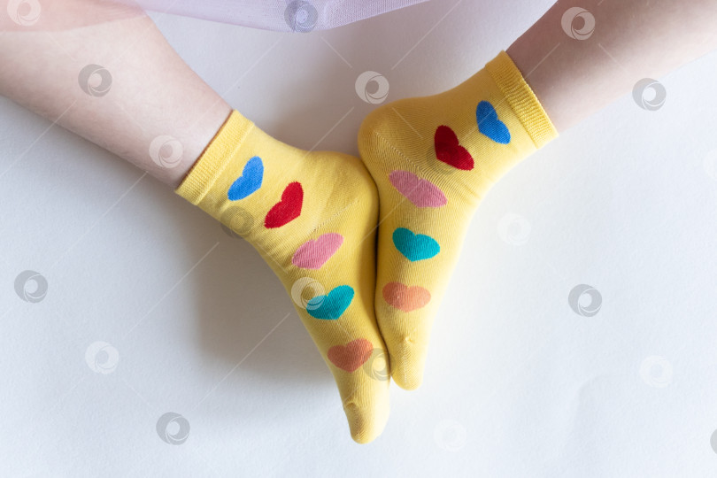 Скачать красивые ножки в теплых носочках с принтом в виде сердечек на белом фоне крупным планом. фотосток Ozero