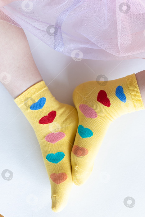 Скачать красивые ножки в теплых носочках с принтом в виде сердечек на белом фоне крупным планом. фотосток Ozero