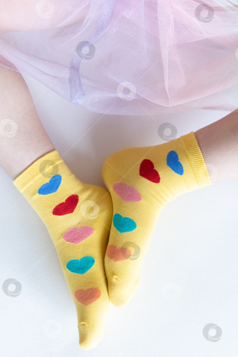 Скачать красивые ножки в теплых носочках с принтом в виде сердечек на белом фоне крупным планом. фотосток Ozero