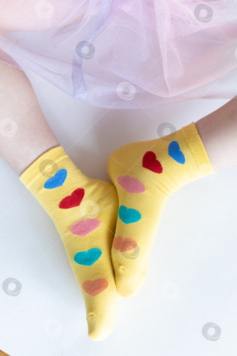 Скачать красивые ножки в теплых носочках с принтом в виде сердечек на белом фоне крупным планом. фотосток Ozero