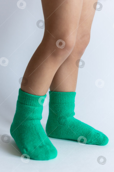 Скачать Ножки 2-летнего ребенка в теплых зеленых носочках на белом фоне фотосток Ozero