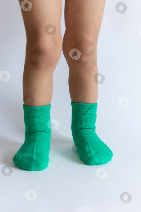 Скачать Ножки 2-летнего ребенка в теплых зеленых носочках на белом фоне фотосток Ozero