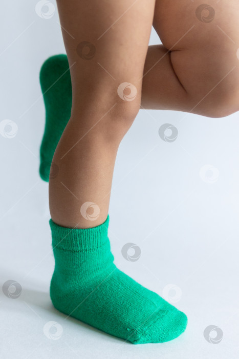 Скачать Ножки 2-летнего ребенка в теплых зеленых носочках на белом фоне фотосток Ozero