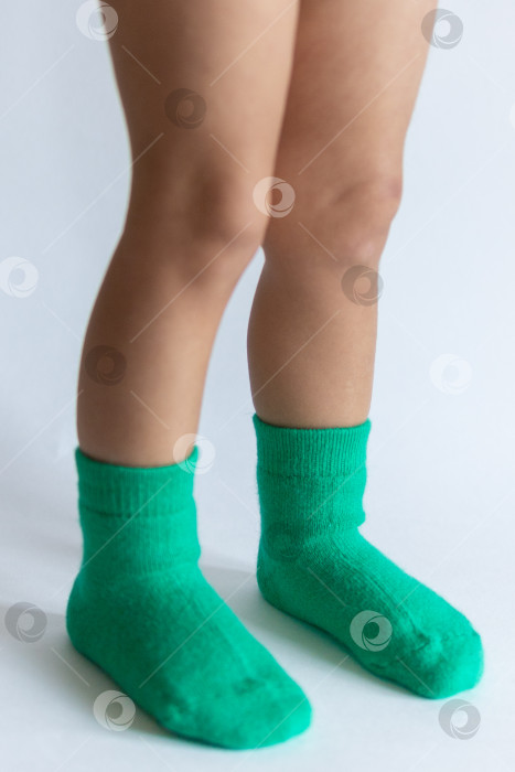 Скачать Ножки 2-летнего ребенка в теплых зеленых носочках на белом фоне фотосток Ozero