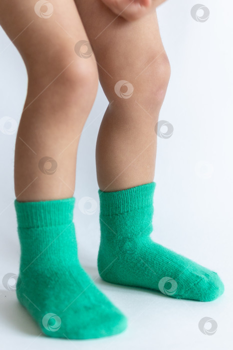 Скачать Ножки 2-летнего ребенка в теплых зеленых носочках на белом фоне фотосток Ozero