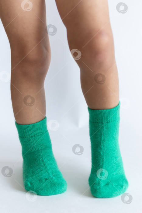 Скачать Ножки 2-летнего ребенка в теплых зеленых носочках на белом фоне фотосток Ozero