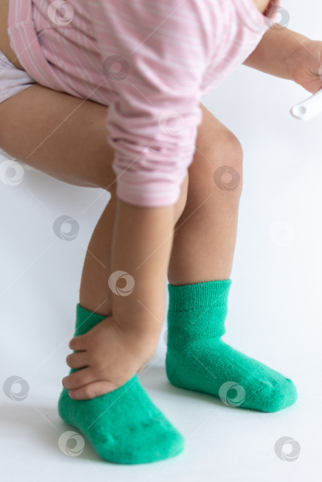 Скачать Ножки 2-летнего ребенка в теплых зеленых носочках на белом фоне фотосток Ozero