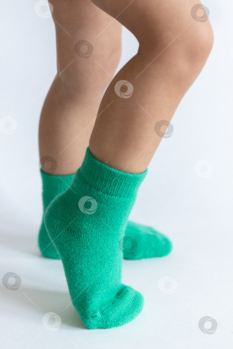Скачать Ножки 2-летнего ребенка в теплых зеленых носочках на белом фоне фотосток Ozero