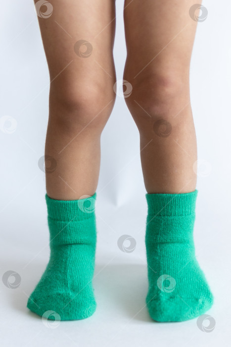 Скачать Ножки 2-летнего ребенка в теплых зеленых носочках на белом фоне фотосток Ozero