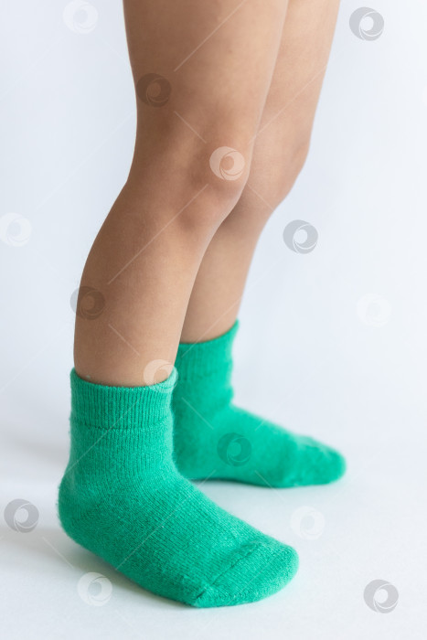 Скачать Ножки 2-летнего ребенка в теплых зеленых носочках на белом фоне фотосток Ozero