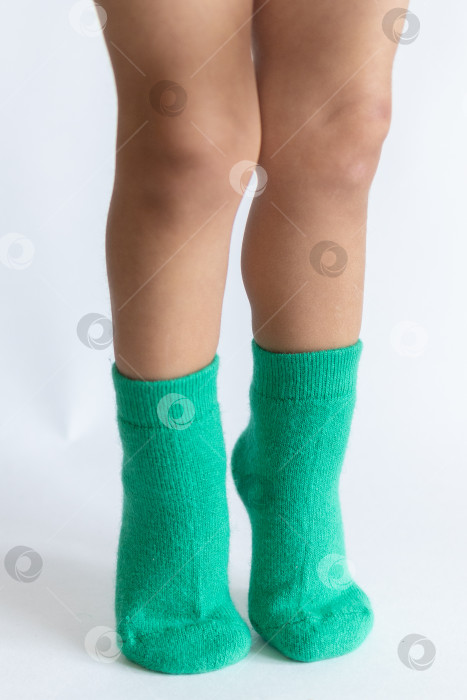 Скачать Ножки 2-летнего ребенка в теплых зеленых носочках на белом фоне фотосток Ozero