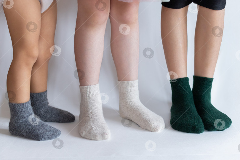 Скачать три пары детских ножек в светлых и темных носках на белом фоне фотосток Ozero