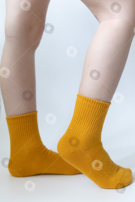 Скачать Детские ножки в желтых носочках на белом фоне фотосток Ozero