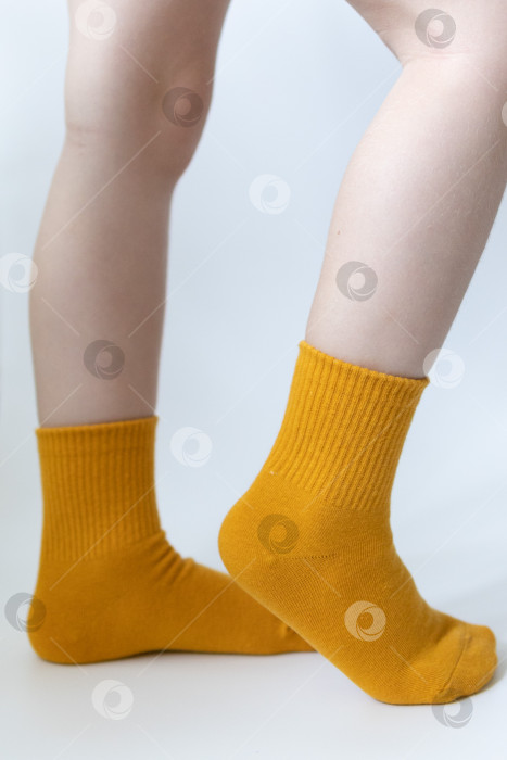 Скачать Детские ножки в желтых носочках на белом фоне фотосток Ozero