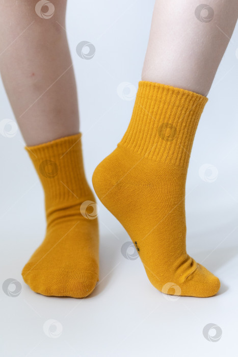 Скачать Детские ножки в желтых носочках на белом фоне фотосток Ozero