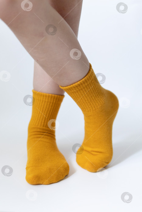 Скачать Детские ножки в желтых носочках на белом фоне фотосток Ozero
