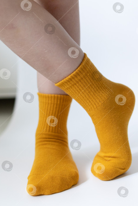 Скачать Детские ножки в желтых носочках на белом фоне фотосток Ozero