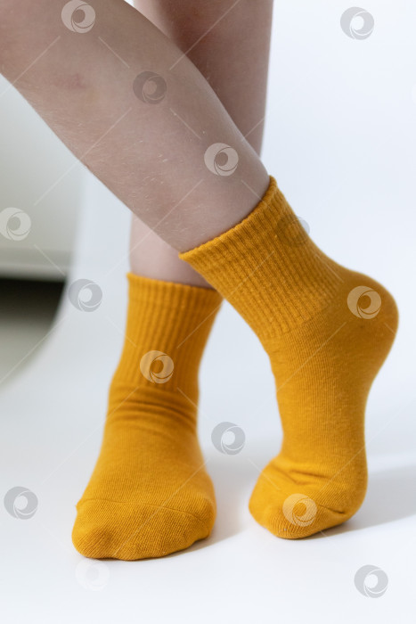 Скачать Детские ножки в желтых носочках на белом фоне фотосток Ozero
