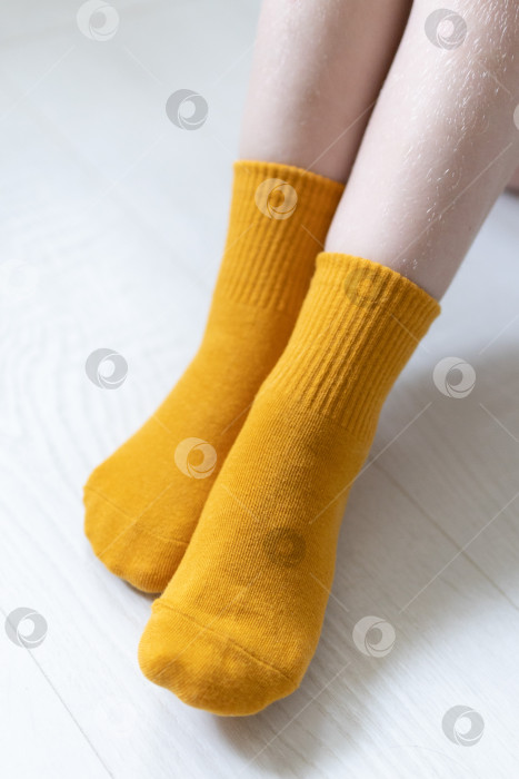 Скачать Детские ножки в желтых носочках на белом фоне фотосток Ozero