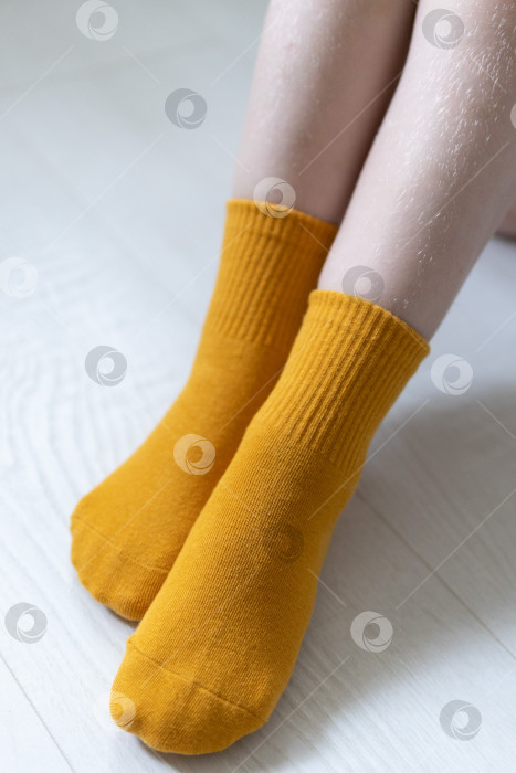 Скачать Детские ножки в желтых носочках на белом фоне фотосток Ozero