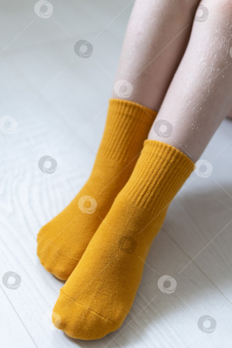 Скачать Детские ножки в желтых носочках на белом фоне фотосток Ozero